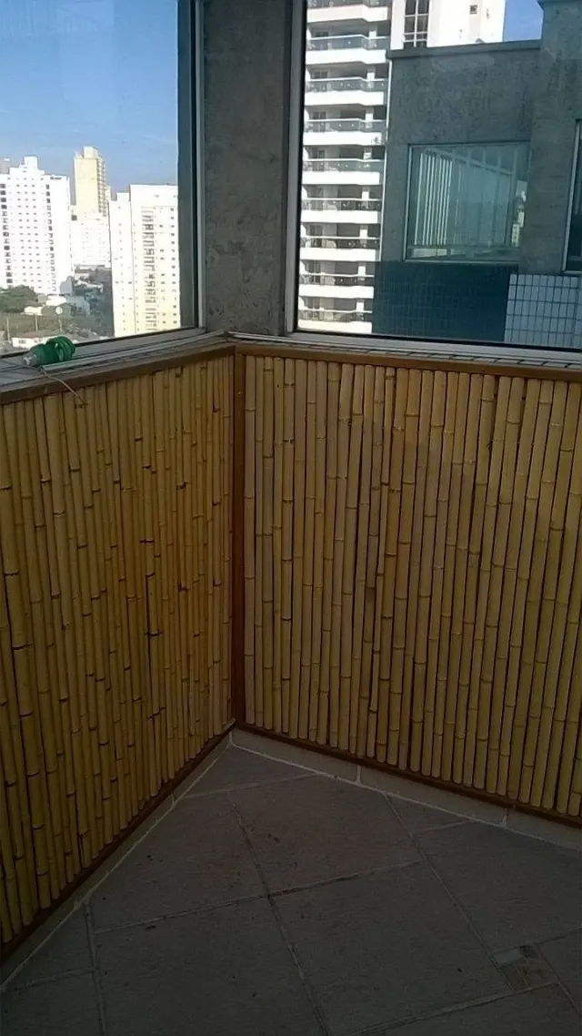 Painéis de bambu com moldura de madeira revestindo a mureta de uma sacada envidraçada
