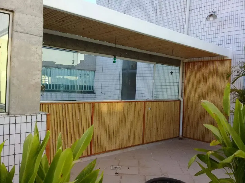 Terraço com forro de bambu na cobertura e painéis de bambu com moldura revestindo mureta e parede